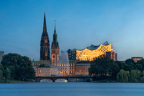 Goldene Elbphilharmonie - Blick über die Außenalster auf das Rathaus, die Nikolaikirche und die Elbphilharmonie - Hamburg Wandbild auf Leinwand, Acrylglas, Akustikbild oder als Poster