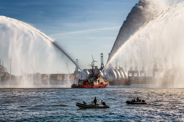 Das Feuerlöschboot „Branddirektor Westphal“ inszeniert ein faszinierendes Wasserspektakel vor der Kulisse des Hamburger Hafens - Wandbild auf Leinwand, Acrylglas, Akustikbild oder als Poster